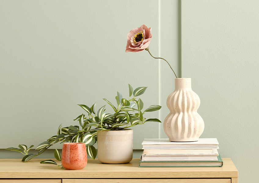 Kunstig plante i potte og papirblomst i en vase