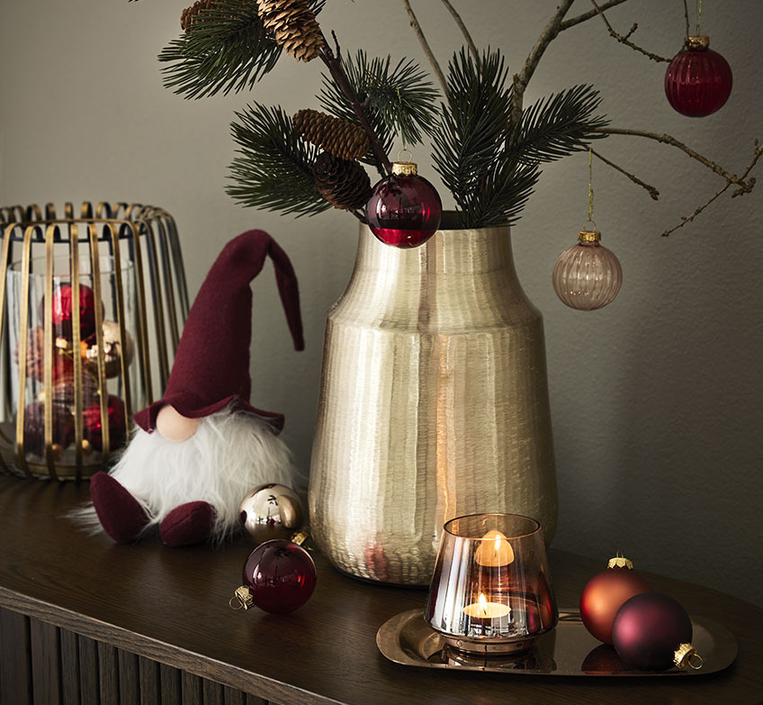 FENJA lysestake fylt med STJERNE julekuler, NABBI julenisse, MALIAS vase og FREKE pyntebrett med BRYNJE telysholder Lanterne i gull, julenisse og gullvase med granbar og julekuler