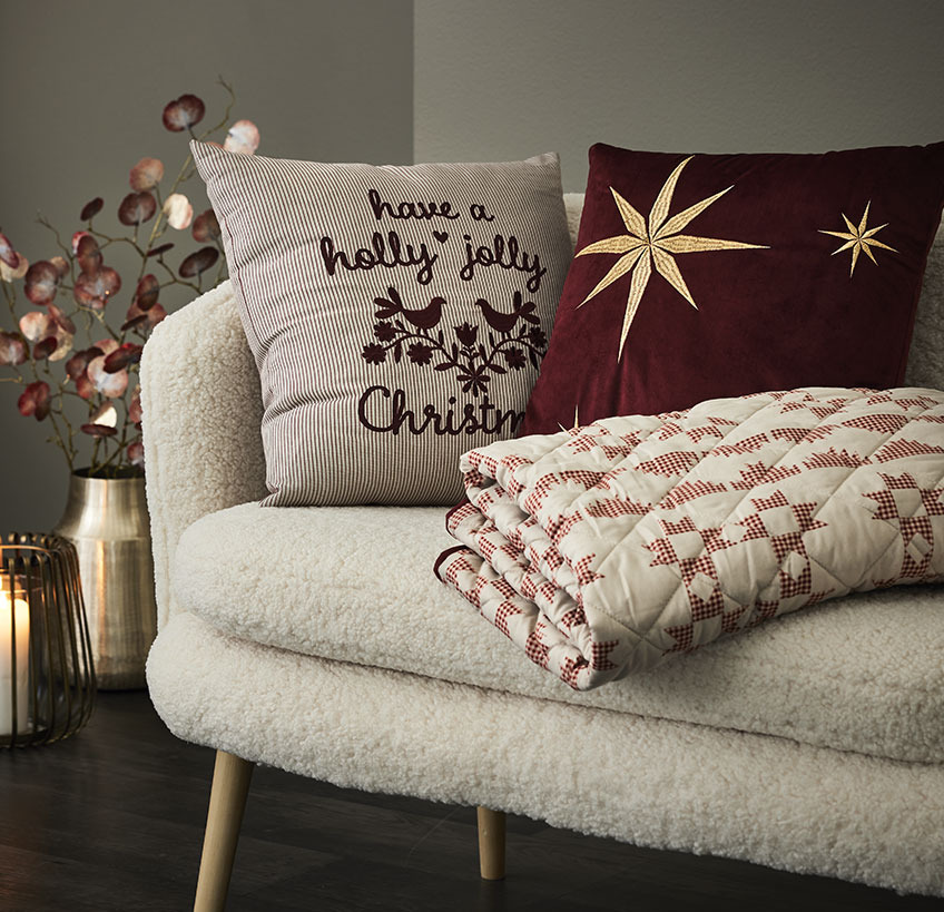 Puter og vattert teppe med julemotiv i en hvit sofa