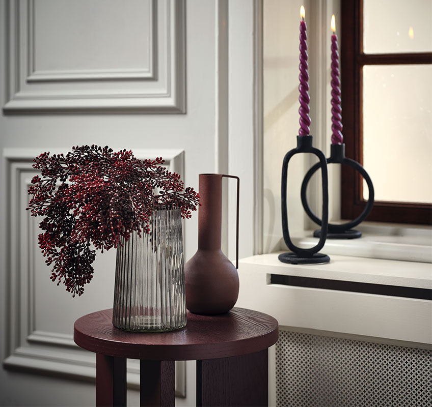 JUL kunstig plante, ADVENT tvistede lys i ELDARIT lysestake Kunstig plante i dyp julerød farge i en glassvase med tvistede lys i bakgrunnen