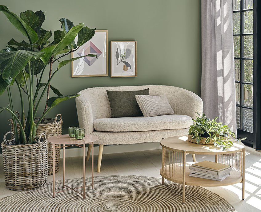 Stue med hvit sofa, salongbord i eik, og grønne planter ved siden av 