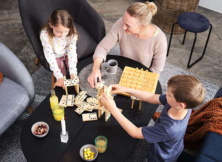 Familie som spiller brettspil på stuebordet Familie som spiller brettspil på stuebordet