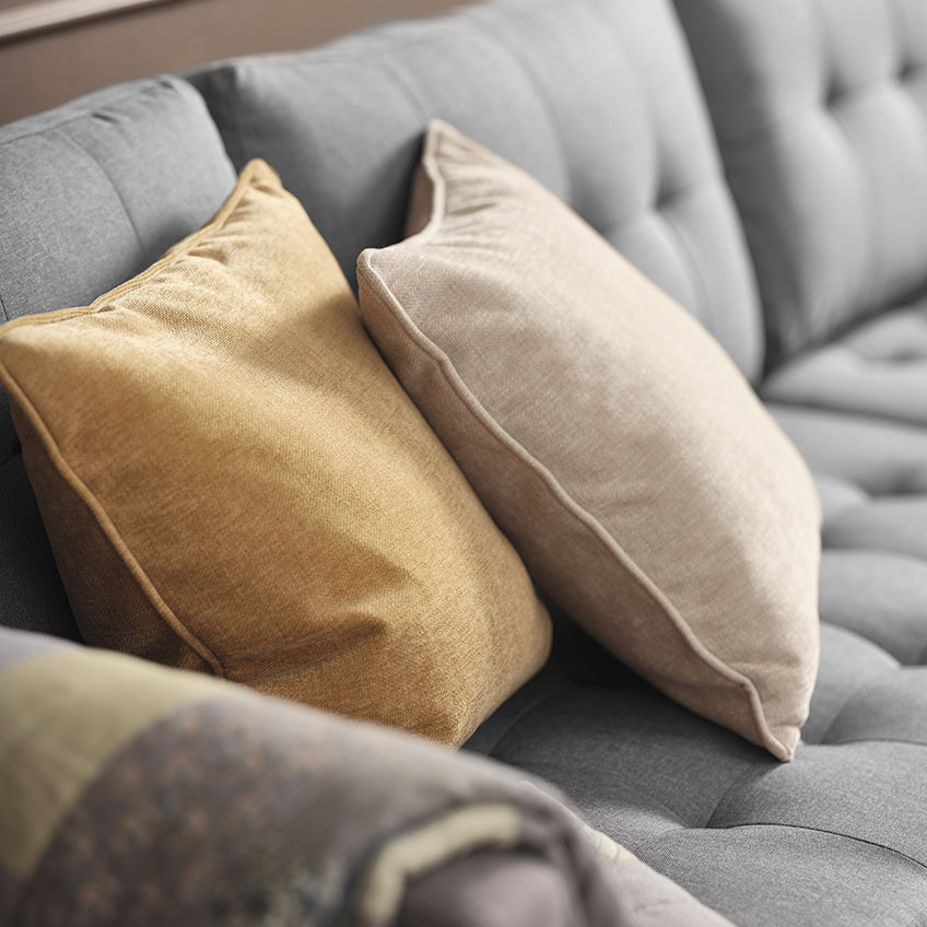 HORNFIOL puter i chenille stoff i gult og beige Chenille puter i gul og beige på en grå sofa