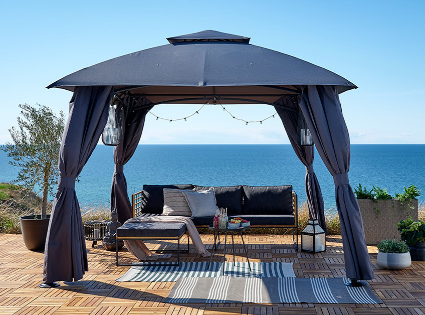 SANKT HANS paviljong og UGILT loungesofa Grå paviljong med loungesett med utsikt over havet