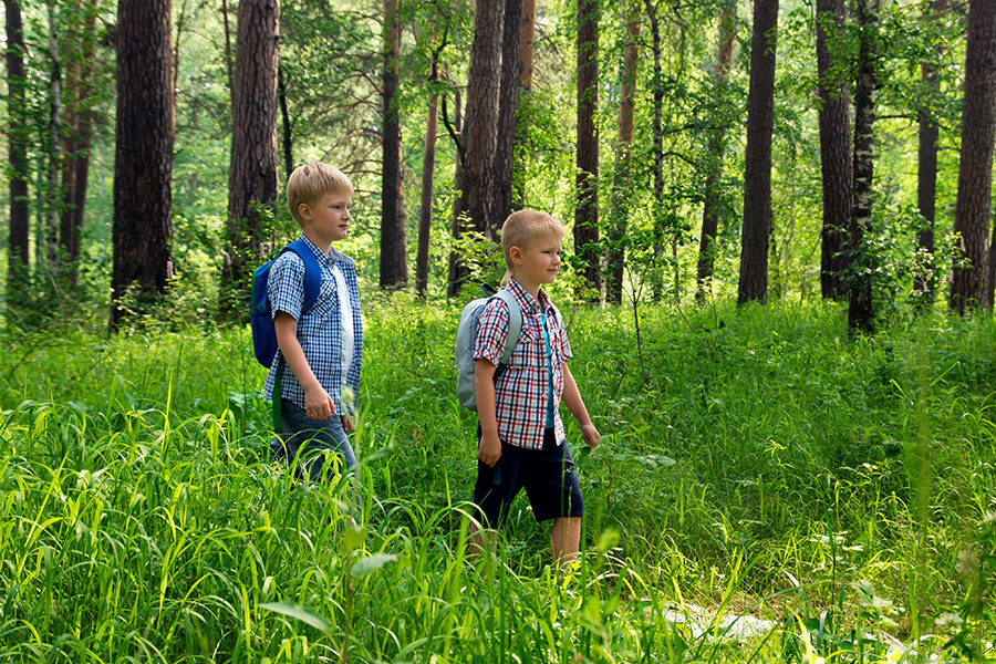 To gutter som går i en skog med ryggsekker
