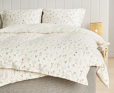 Sommerlig sengesett med mønster av markblomster på en offwhite bakgrunn
