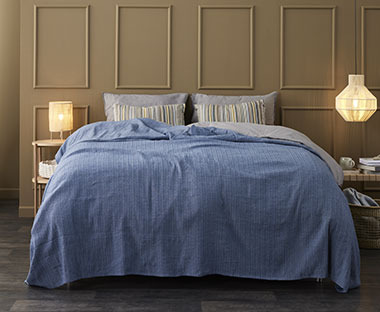 Blått sengeteppe med vevet med en grov tekstur