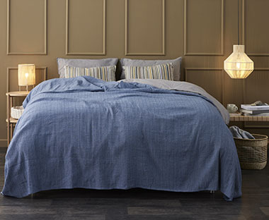 Blått sengeteppe med dekorativ struktur i tekstilet