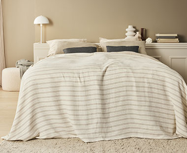 Garnfarget sengeteppe med striper i beige og jordtoner