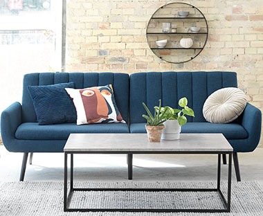Et stilig sofabord i betong look foran en blå sofa