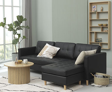 Mørkegrå og minimalistisk sofa i et mintgrønt rom